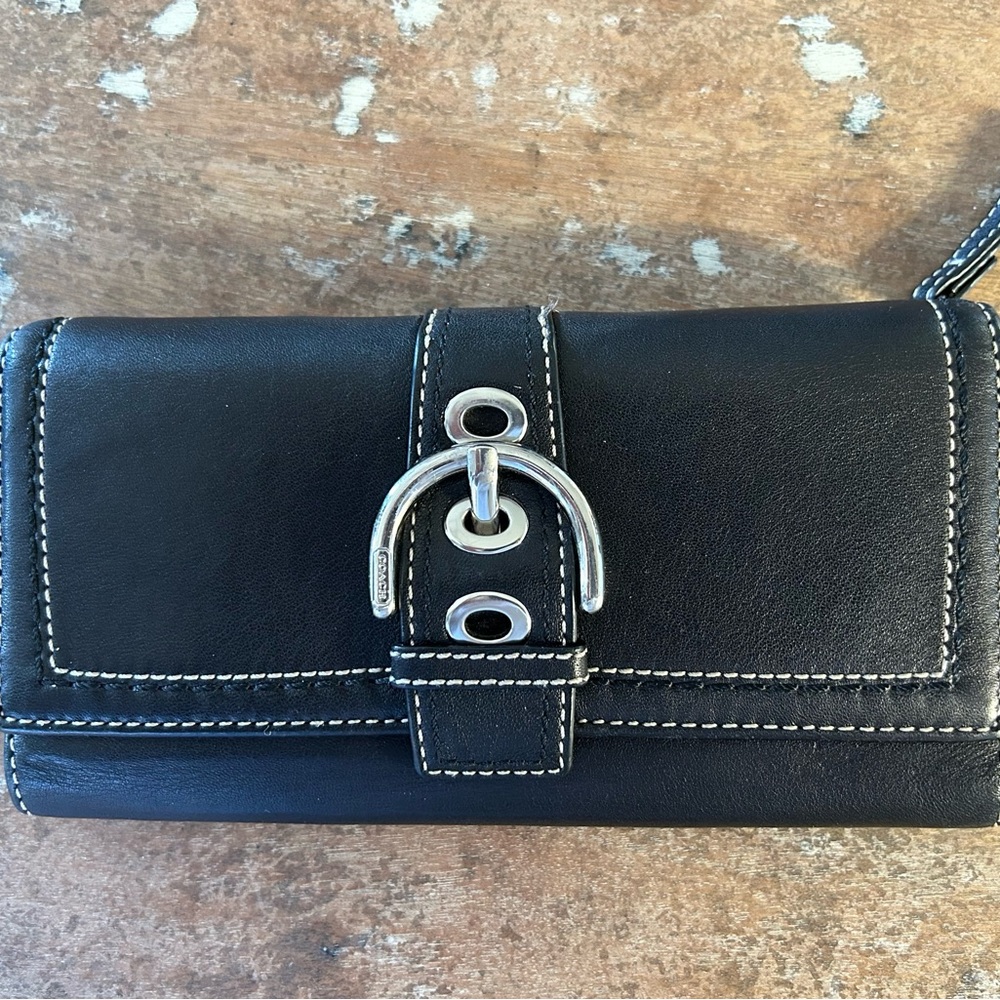 Black leather coach wallet with silver buckle.